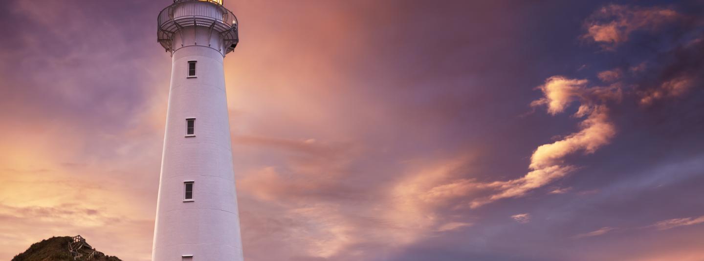 A white lighthouse against a purple sky