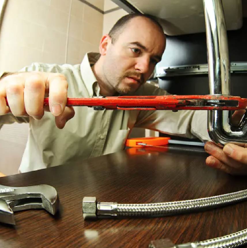 A plumber using a wrench to work on a pipe