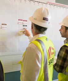 Construction workers in hard hats working on a whiteboard